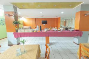 una gran cocina con una mesa rosa en el centro en OYO Real Palace Hotel, Teresina, en Teresina