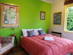 a green bedroom with a large bed and a chair at City central apartment – modern, private & quiet in Invercargill