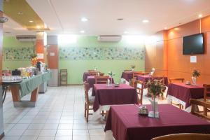 a restaurant with purple tables and chairs and a tv at OYO Real Palace Hotel, Teresina in Teresina