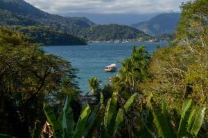 a boat in a large body of water with mountains at Pousada Vitorino in Angra dos Reis