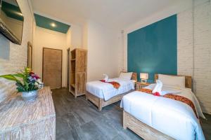 a hotel room with two beds and flowers in it at EUFORIA Guest House in Canggu