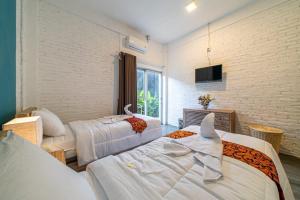 a hotel room with two beds and a tv at EUFORIA Guest House in Canggu
