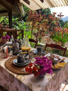 a table with plates of food and flowers on it at Pousada Vitorino in Angra dos Reis