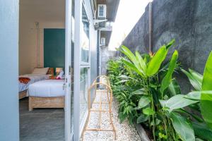 Habitación con balcón, cama y plantas. en EUFORIA Guest House en Canggu