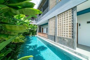 a swimming pool in front of a house with plants at EUFORIA Guest House in Canggu
