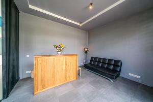a waiting room with a black leather couch and a table at EUFORIA Guest House in Canggu