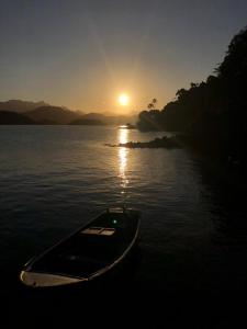 ein Boot, das bei Sonnenuntergang auf dem Wasser sitzt in der Unterkunft Pousada Vitorino in Angra dos Reis