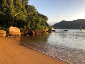 a sandy beach next to a body of water at Pousada Vitorino in Angra dos Reis