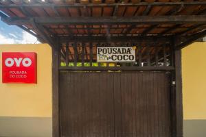 una puerta de madera con un cartel en la parte superior en OYO Pousada Do Coco, Porto Seguro, en Porto Seguro