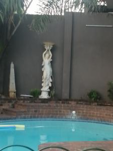 a statue of a cat sitting next to a swimming pool at Naisar's Apartments Primrose,Johannesburg in Johannesburg