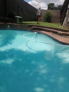duży basen z niebieską wodą na dziedzińcu w obiekcie Naisar's Apartments Primrose,Johannesburg w mieście Johannesburg