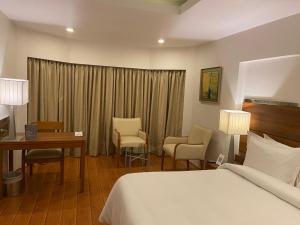 
a hotel room with a bed, chair, desk and a television at The Residency, Chennai in Chennai

