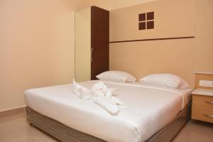 a bedroom with a bed with white sheets and pillows at Murali's Kudil in Mayiladuthurai