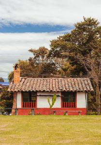 a small red and white house in a field at Hotel y Centro de Convenciones Pueblito de Yerbabuena Paraíso Natural in Chía