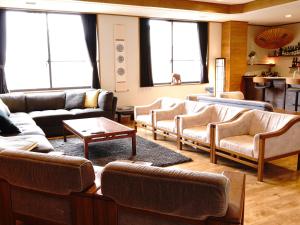 a living room with couches and tables and windows at Refre Hotel in Myoko