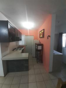 uma cozinha com paredes cor de laranja e bancadas brancas em Casa "Linda Vista" em Cuatrociénegas de Carranza