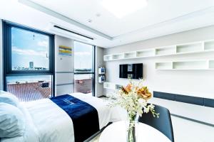 江陵市的住宿－Hi Ocean Gyeongpo，一间卧室,配有一张床,桌子上放着花瓶