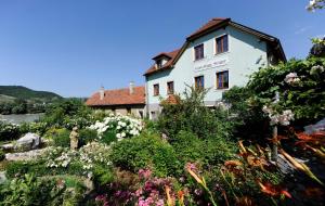 a white house with flowers in front of it at Winzerhof - Gästehaus Stöger in Dürnstein