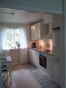 una cucina con armadi bianchi, lavandino e finestra di Björkslingan a Vimmerby