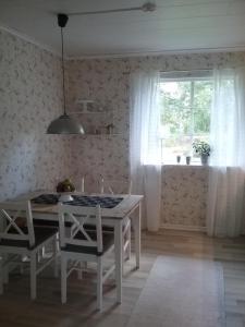 ein Esszimmer mit einem Tisch, Stühlen und einem Fenster in der Unterkunft Björkslingan in Vimmerby