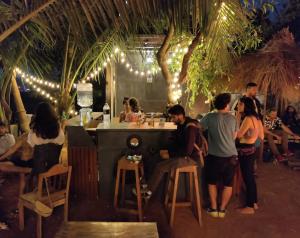 a group of people standing around a bar with lights at Wonderland Hostel in Anjuna