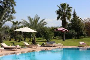 una piscina con tumbonas y sombrillas junto a una piscina en La Vie En Rose, en Marrakech