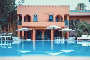 a resort with a swimming pool with chairs and umbrellas at La Vie En Rose - Horses & Dogs House in Marrakesh
