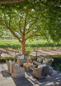 a patio with couches and a table and a tree at La Clé Lodge in Franschhoek