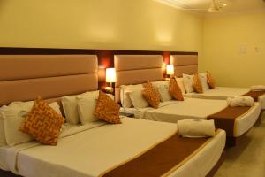 a hotel room with three beds with pillows at Hotel Ocean Heritage in Kanyakumari