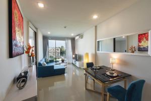 a living room with a table and a blue couch at First Choice Grand Suites Sha Plus Extra in Hua Hin