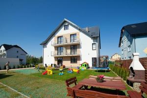 a house with kids playing in the yard in front of it at Willa Północna II in Karwia