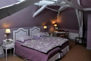 - une chambre avec un grand lit aux murs violets dans l'établissement La Demeure de l'Ile, à Craon