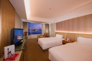 um quarto de hotel com duas camas e uma televisão de ecrã plano em Shu Guang International Hotel em Nanquim