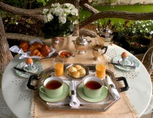 una mesa con dos tazas de té y una bandeja de comida en La Demeure de l'Ile en Craon