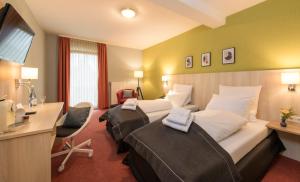 a hotel room with two beds and a desk at City Hotel Meckenheim in Meckenheim