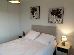 1 dormitorio con 1 cama blanca con 2 lámparas y 2 fotografías en Béguinage le Val d'Or, en Paray-le-Monial