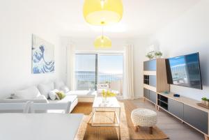 a living room with a white couch and a tv at Higuerón Rental Playa Apartamento in Benalmádena