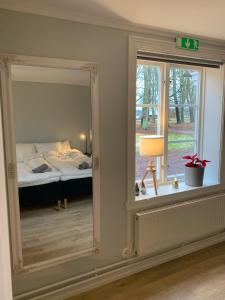 een spiegel in een kamer met een bed en een raam bij Segerstadsby Gårdshotell AB in Vålberg