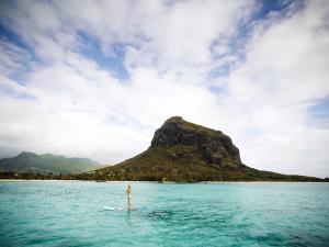 a person on a surfboard in the middle of a body of water at LUX* Le Morne Resort in Le Morne