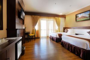 a hotel room with two beds and a desk at Royal Darmo Malioboro in Yogyakarta