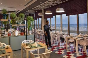 杜拜的住宿－Riu Dubai Beach Resort - All Inclusive，站在带桌椅的餐厅里的人