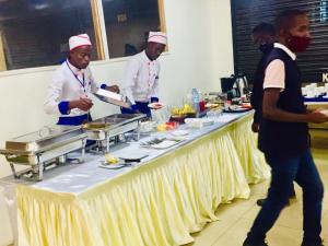 un grupo de chefs parados alrededor de una mesa con comida en Shangri-La Fortune Hotel en Kampala