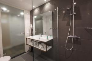 ein Bad mit einer Dusche, einem Waschbecken und einem Spiegel in der Unterkunft Hotel Zeezicht in Oost-Vlieland