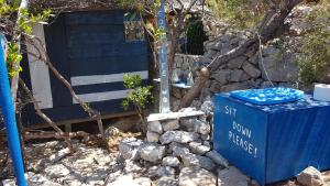 islandescape-bisevo في بيشيفو: وجود صندوق ازرق جالس بجانب كومه من الصخور