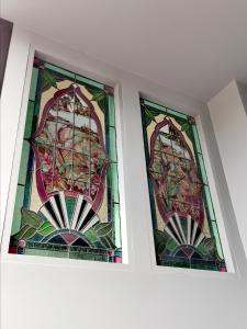 twee glas-in-loodramen aan de zijkant van een muur bij Refresh109 on Cameron in Launceston