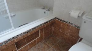 a bathroom with a bath tub and a toilet at Lochinver Holiday Lodges & Cottages in Lochinver