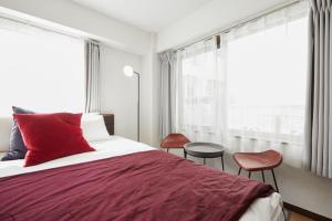 東京にあるHOTEL AIS HATAGAYAのベッドルーム1室(赤いベッド1台、椅子2脚付)