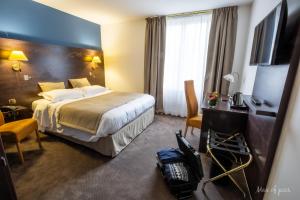 a hotel room with a bed and a desk and a television at Élysée Hôtel in Châteauroux +52 photos