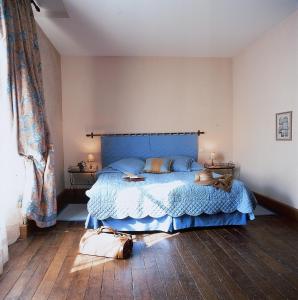 Schlafzimmer mit einem Bett mit blauer Tagesdecke in der Unterkunft Hôtel Les Orangeries in Lussac-les-Châteaux