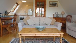 ein Wohnzimmer mit einer weißen Couch und einem Tisch in der Unterkunft Lochinver Holiday Lodges & Cottages in Lochinver